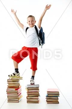 Diligent preschooler standing on the top of book stairs with his arms raised Stock Photos