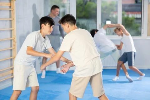 Diligent preteen student practicing self-defense techniques in pairs Stock Photos