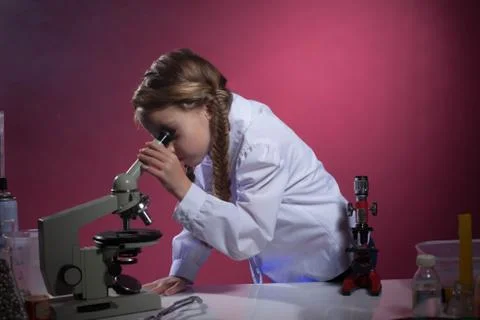 Diligent schoolgirl looking through microscope Stock Photos