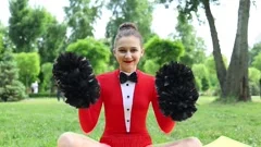 A cheerleader shakes her pom-poms smiles and encourages action