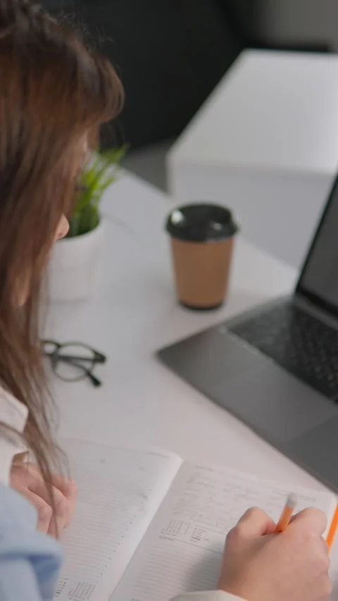 The diligent student at the university desk is fully focused on taking detailed Stock Footage 280379591