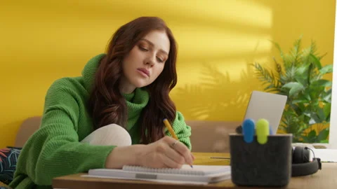 Diligent young brunette making notes, searching information, studying at home Video stock 245838457