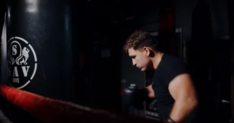 In a dim boxing ring, a determined man showcases his skills in an intense match Stock Footage 312624820