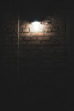Dim light from lamp on brick wall, incandescent light bulb in glass shade, di Foto stock