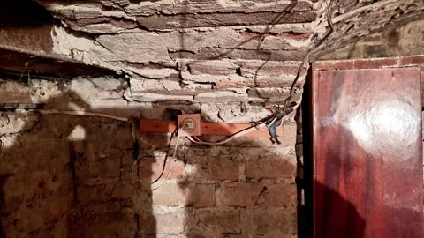 Dim Rustic Basement with Exposed Brick Ceiling, Wooden Beam, and Old Door Stock Footage 332322803