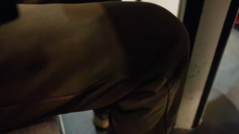 Dim subway knee resting on seat, close view of khaki pant and urban metal pole Stock Footage 338287203