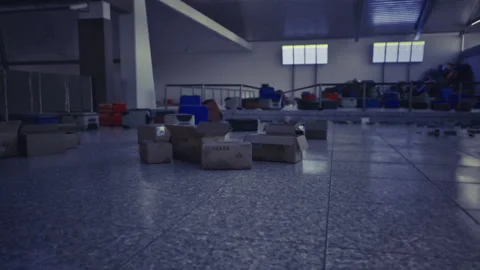 Dim warehouse staging area with scattered crates logistics worker shift Stock Footage 330115998