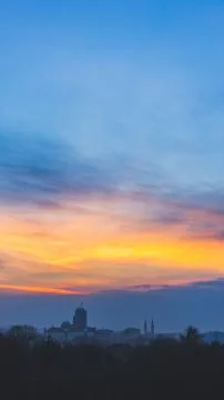 Dim winter twilight. Clouds at sunset over dark industrial town. Stock Photos
