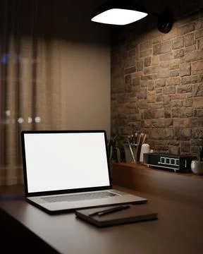 Dim workspace with white screen laptop and digital clock on table beside br.. 스톡 일러스트