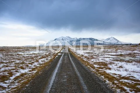 Diminishing Perspective Of Road On Snow Covered Scrubland To Snow Capped