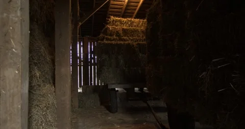 Dimly Lit Barn Interior with Stacked Hay Bales and Wooden Beams Stock Footage 333227962