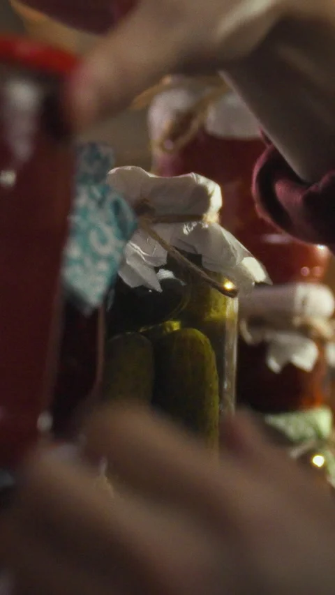 In a dimly lit cellar a man meticulously arranges jars of canned food on a s Stock Footage 334397996