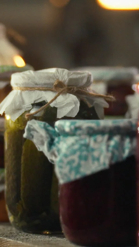 In a dimly lit cellar a mans hand gently sets a clear jar of homemade pickle Stock Footage 334398340