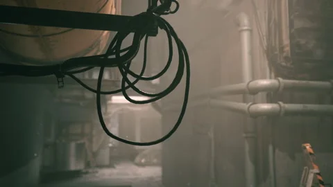 Dimly lit corridor with pipes and hanging cables in an industrial space Stock Footage 331422321