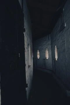 Dimly lit corridor with small windows in an ancient building Foto stock
