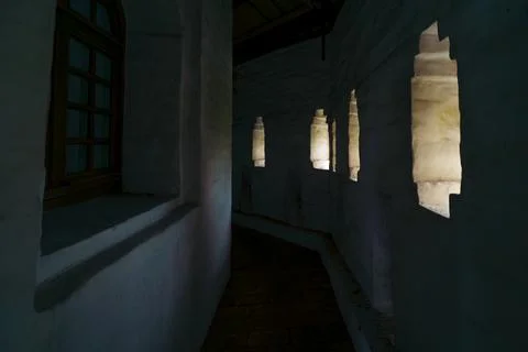 Dimly lit corridor with small windows in an ancient building Stock Photos