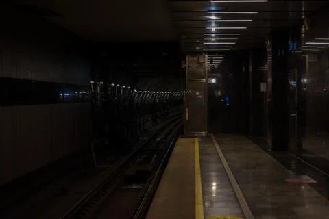 A dimly lit empty subway or metro station platform with the tracks disappearing Stock Photos