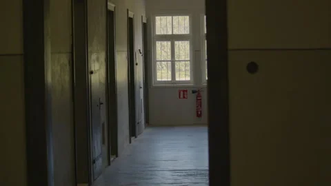 A dimly lit prison corridor with a row of metal doors on the left Stock Footage 299038169