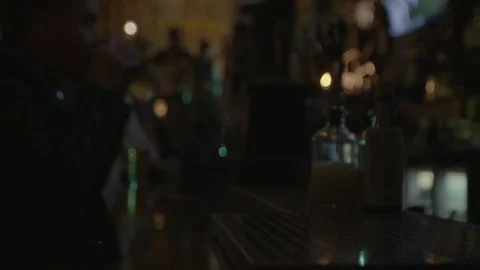Dimly Lit Pub Bar Counter with Drinks and Patrons Stock Footage 343956086