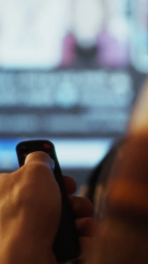 In a dimly lit room a person skillfully uses a remote control device to navi Stock Footage 331600151