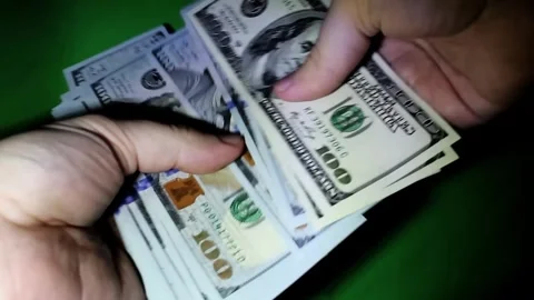 In a dimly lit room, two hands engage in a swift exchange of cash, showcasing a Stockbeeldmateriaal 292751476