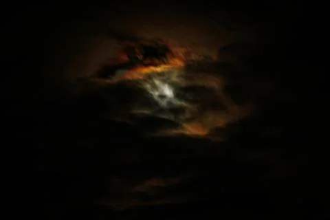 A dimly lit sky with dark clouds reveals subtle iridescent shades of orange. Stock Photos