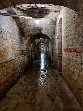 Dimly lit stone corridor inside an underground fort bunker passage Fotos Stock