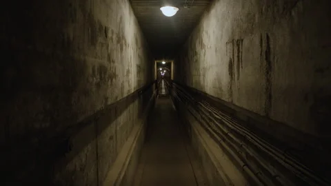 A dimly lit underground passage with overhead lights, concrete walls Stock Footage 301033568