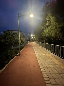 Dimly Lit Walking Path Along Sidewalk with Streetlamp Illumination in Limas.. Stock Photos