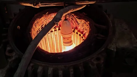 Dimly lit workshop scene featuring a burning tungsten bulb inside a motor coil,  Stock Footage 345831187