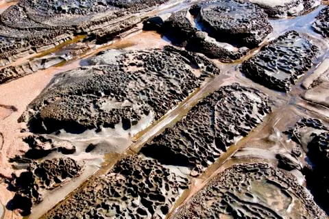 Dimpled and rectangular pattern in rocks on seashore Foto stock