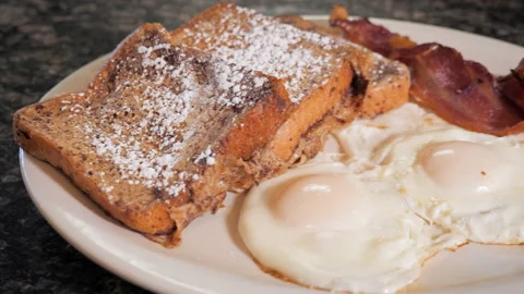 Diner breakfast on white plate, French toast fried eggs and bacon // Stock Footage