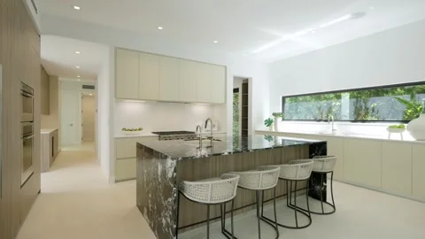 Dining area with four bar chairs standing in row by luxury kitchen aisle in Stock Footage 282285648