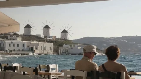 A dining couple enjoy the view of the windmills on mykonos Stock Footage 69245924