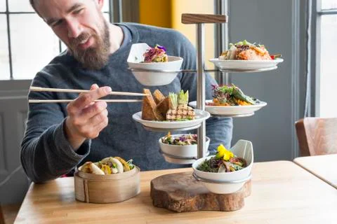 Dining Customer Takes Tofu Using Chopsticks from Tiered Server Stock Photos