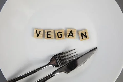 Dining plate with fork and knife with the text VEGAN, concept of dieting vs Stock Photos