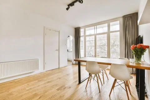 A dining room with a large window and a table Stock Photos