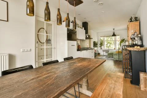 A dining room with a long table and a kitchen 写真素材