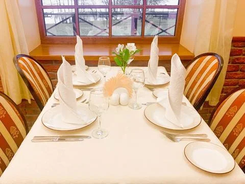 The dining table is covered with a white tablecloth, there are appliances on the Stock Photos