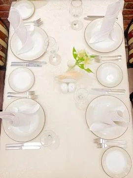 The dining table is covered with a white tablecloth, there are appliances on the Stock Photos