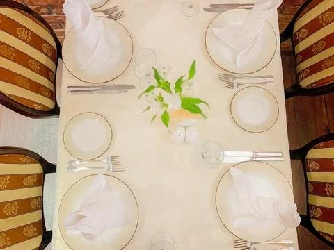 The dining table is covered with a white tablecloth, there are appliances on the Stock Photos