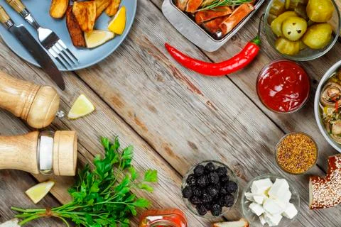 Dining table with grilled meat, rustic potatoes and pickled cucumbers. Concep Fotos de archivo