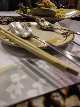 Dining table holds empty plates with spoons and chopsticks Stock Photos
