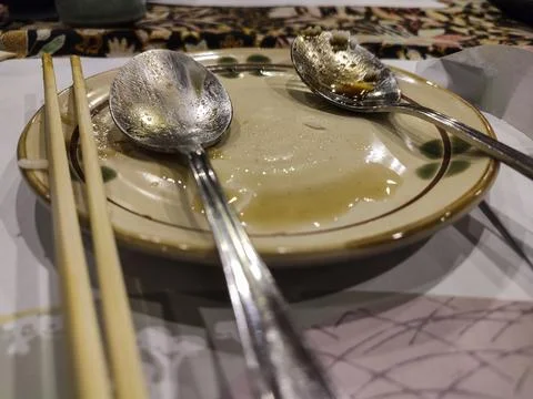 Dining table holds empty plates with spoons and chopsticks Stock Photos