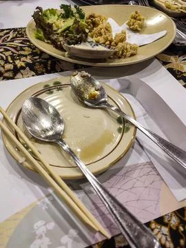 Dining table holds empty plates with spoons and chopsticks Stock Photos