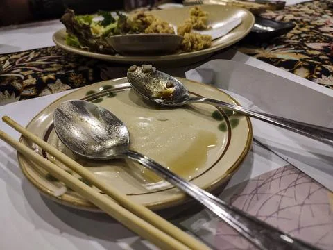 Dining table holds empty plates with spoons and chopsticks Stock Photos