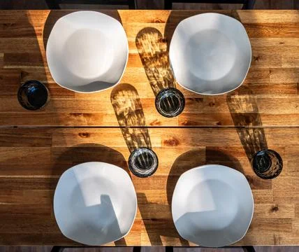 Dining table set for four from above. Plates and glasses cast strong sunlig.. Stock Photos