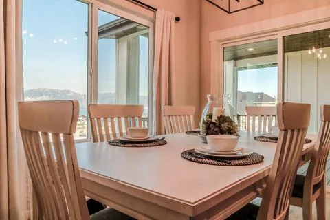 Dining table set for four persons with view of the neighborhood through windows Stock Photos