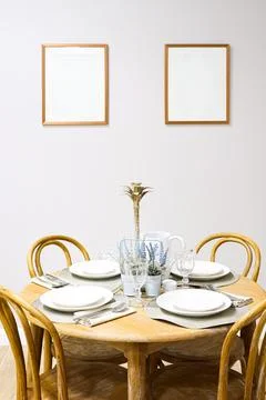 Dining table set for four with rustic wooden furniture and blank picture fr.. Stock Photos