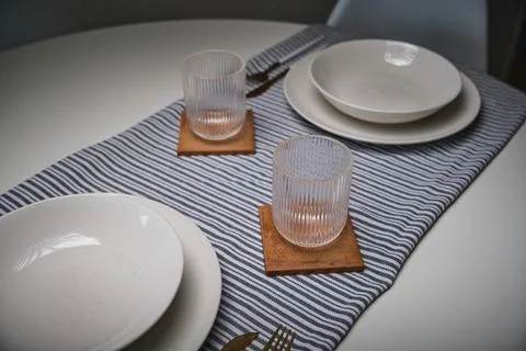 Dining table set with minimalist tableware and striped runner 스톡 사진